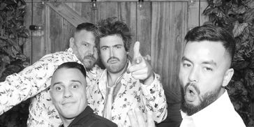 Four men posing in a playful black and white photo.