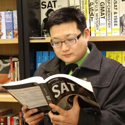 Man studying SAT prep book in a library or bookstore.