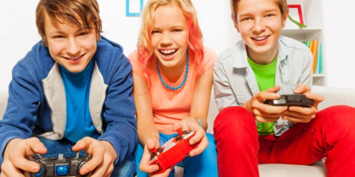 Three happy teenagers playing video games together indoors.