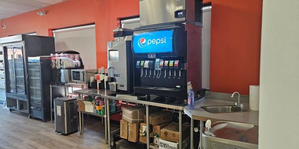 A beverage station with a Pepsi soda dispenser and other drink machines.