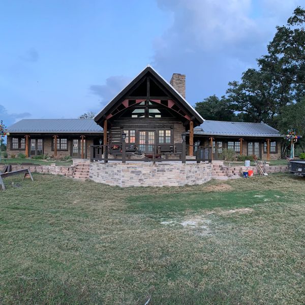 A one story house being constructed with trees in the back