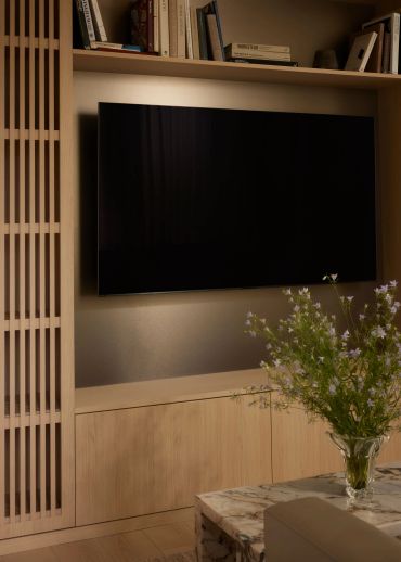 Modern living room with TV and flowers in a vase.