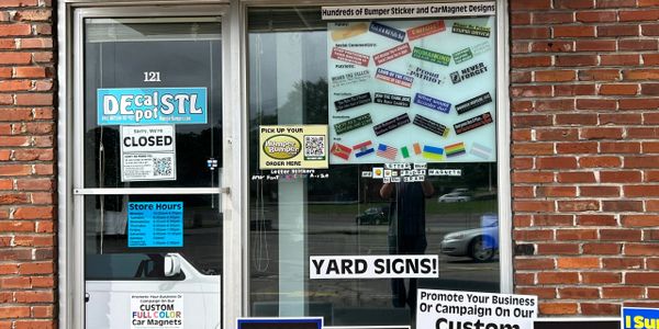 A closed storefront for Decal Spot STL with various bumper and car magnet stickers displayed.