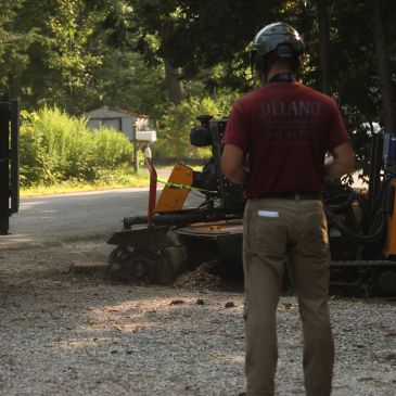 Person in helmet operating a remote-controlled robotic machine outdoors.