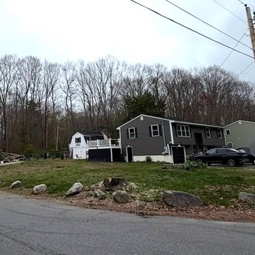 A suburban house with a large yard and leafless trees in the background.