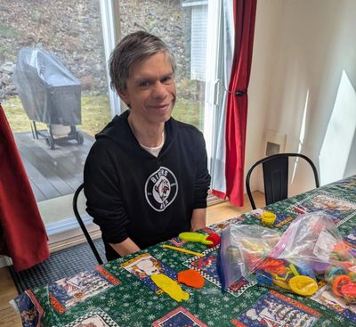 Man sitting at a table with craft supplies and holiday-themed tablecloth.