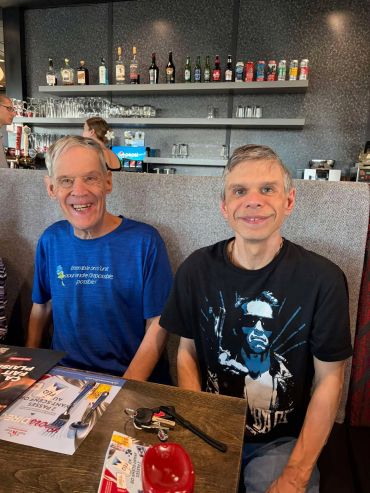 Two men smiling at a restaurant table with drinks and menus.