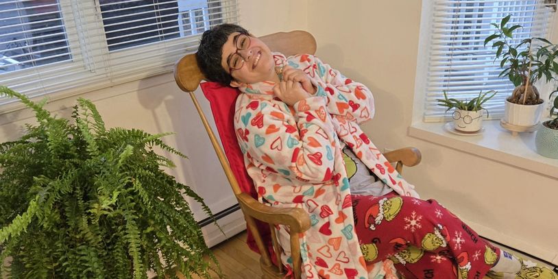 Person in cozy heart-patterned pajamas relaxing in a wooden rocking chair.