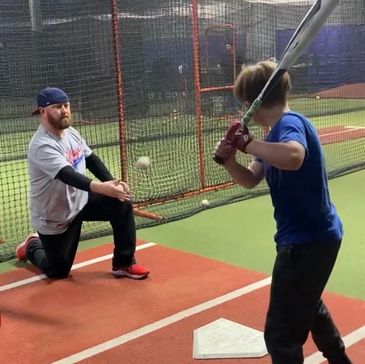 two people doing batting practice in a batting cage