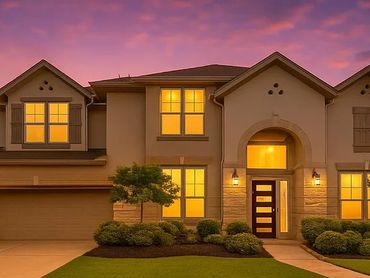 Large modern house with warm lights at sunset.
