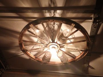 Farmhouse chandelier using reclaimed Hainer liquor bottles and wagon wheel