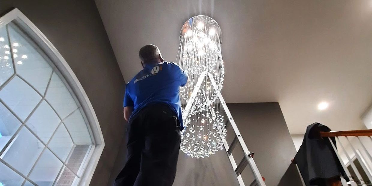Doctor Electric team member installing chandelier