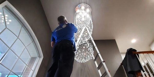 Doctor Electric tech installing a chandelier