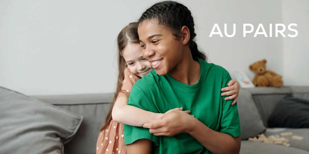 A young woman and a younger girl smile and hug with the words 'AU PAIRS'