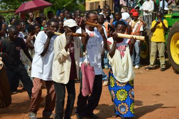 Men playing traditional wooden flutes in a lively outdoor gathering.