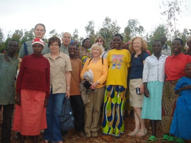 A diverse group of people posing outdoors, some wearing colorful clothing and a Santa hat.