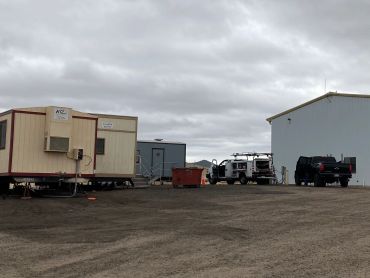 A construction or work site with trailers and vehicles under cloudy skies.