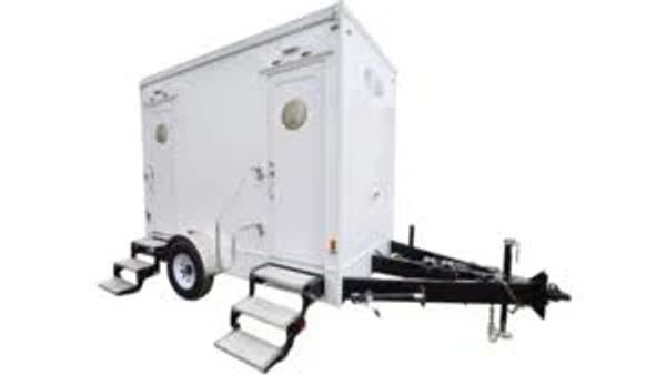Portable restroom trailer with stairs and white exterior.