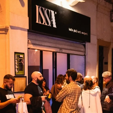 Group of people socializing outside ISSA venue at night.