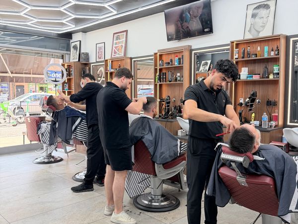 Barbers cutting customers' hair in a salon.