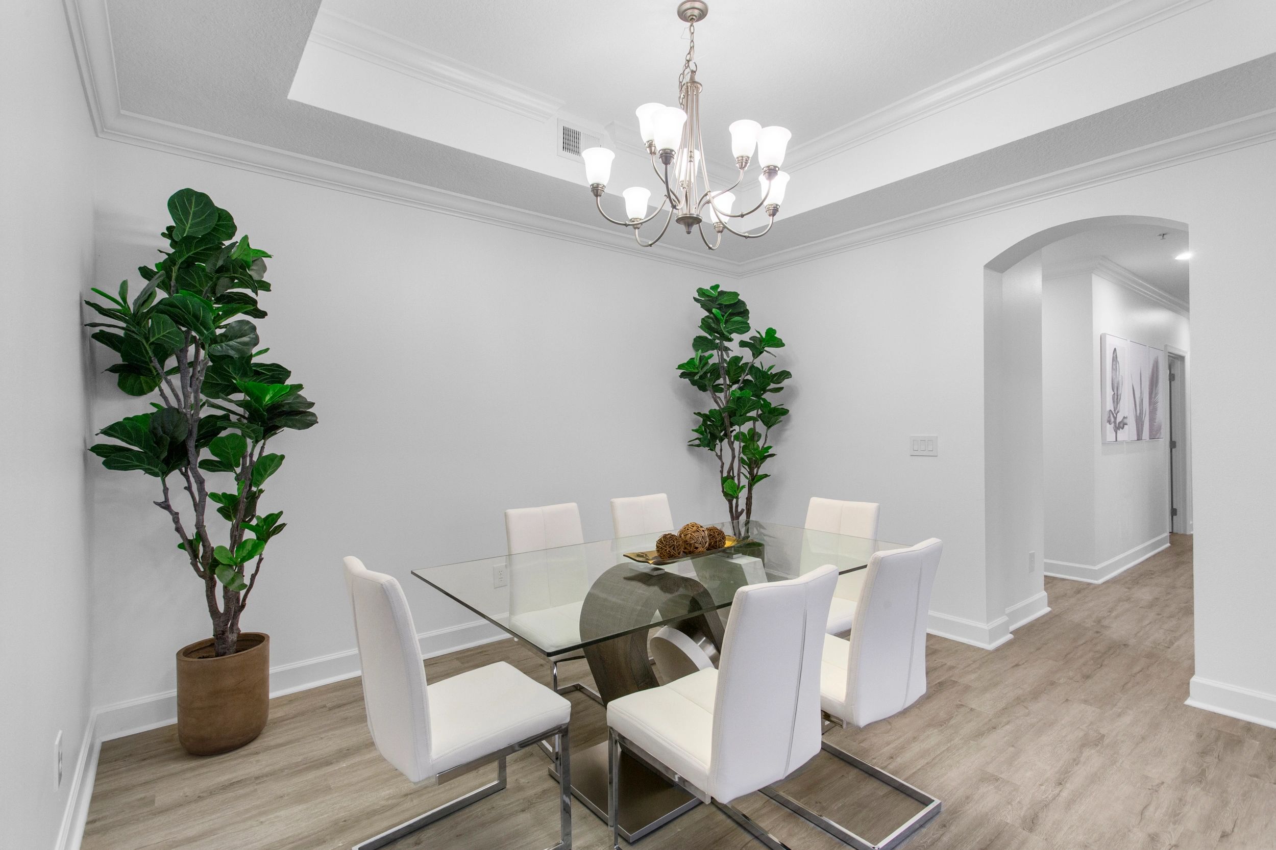 Modern dining room with glass table and white chairs.