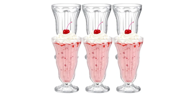 Three strawberry milkshakes with whipped cream and cherries.
