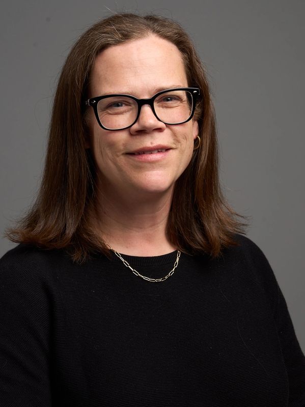 Woman with glasses smiling, black top.