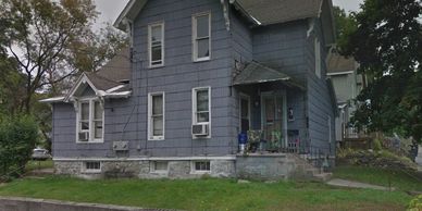 Old blue two-story house with a grassy lawn.