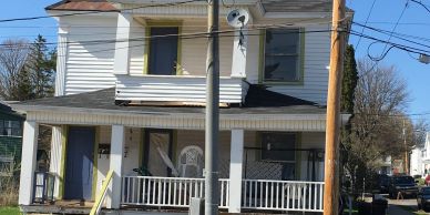 Old two-story house with front porch and satellite dish.