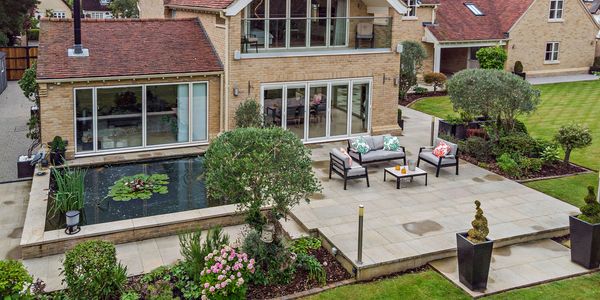 Elegant backyard patio with outdoor seating and a pond surrounded by greenery.
