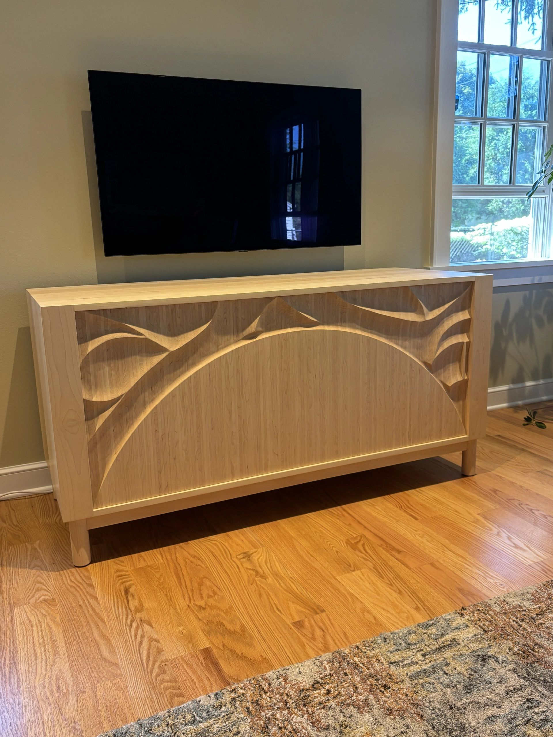 Wooden cabinet with intricate carved design under wall-mounted TV.