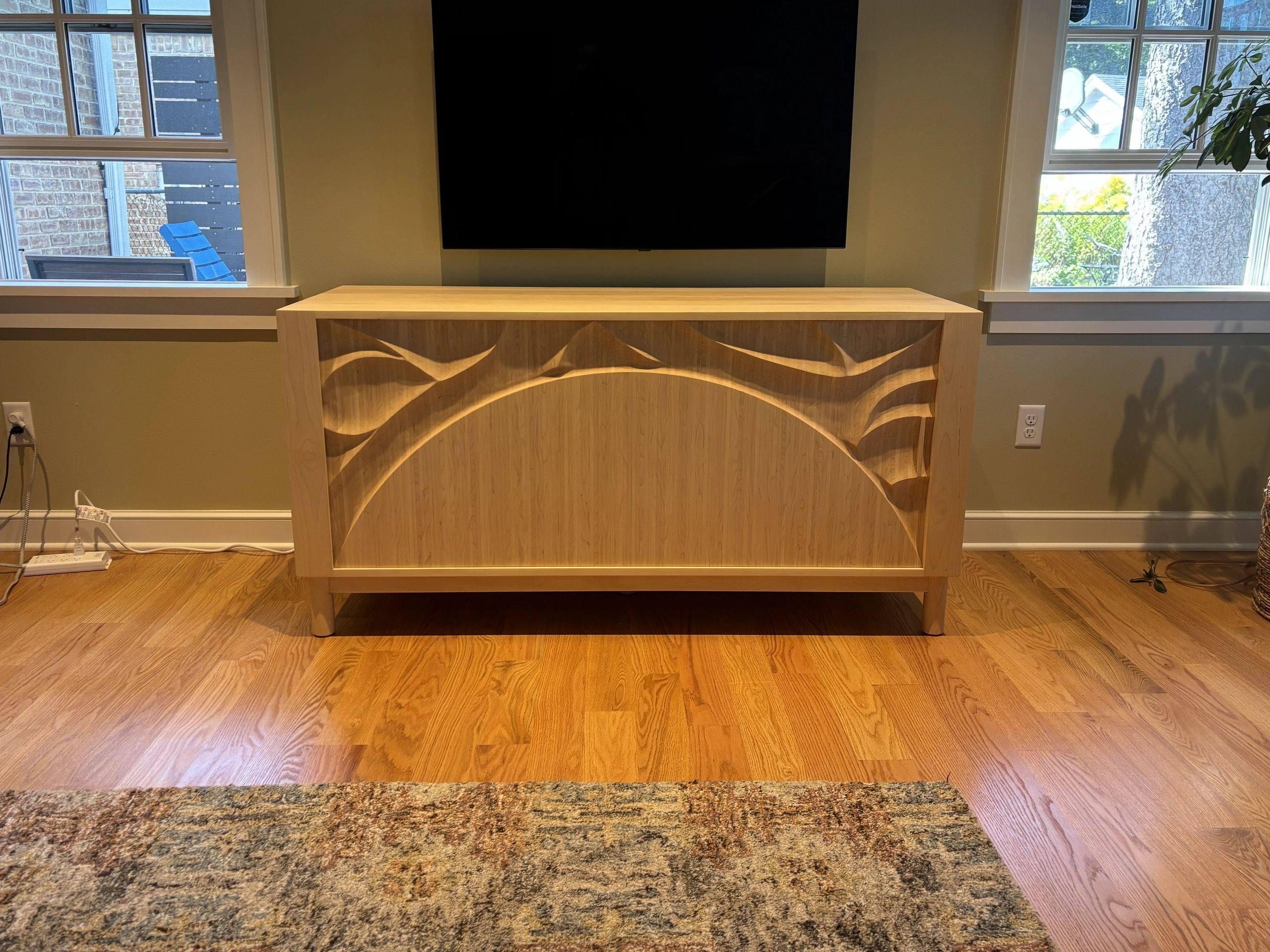 Wooden cabinet with artistic carved design beneath a TV.