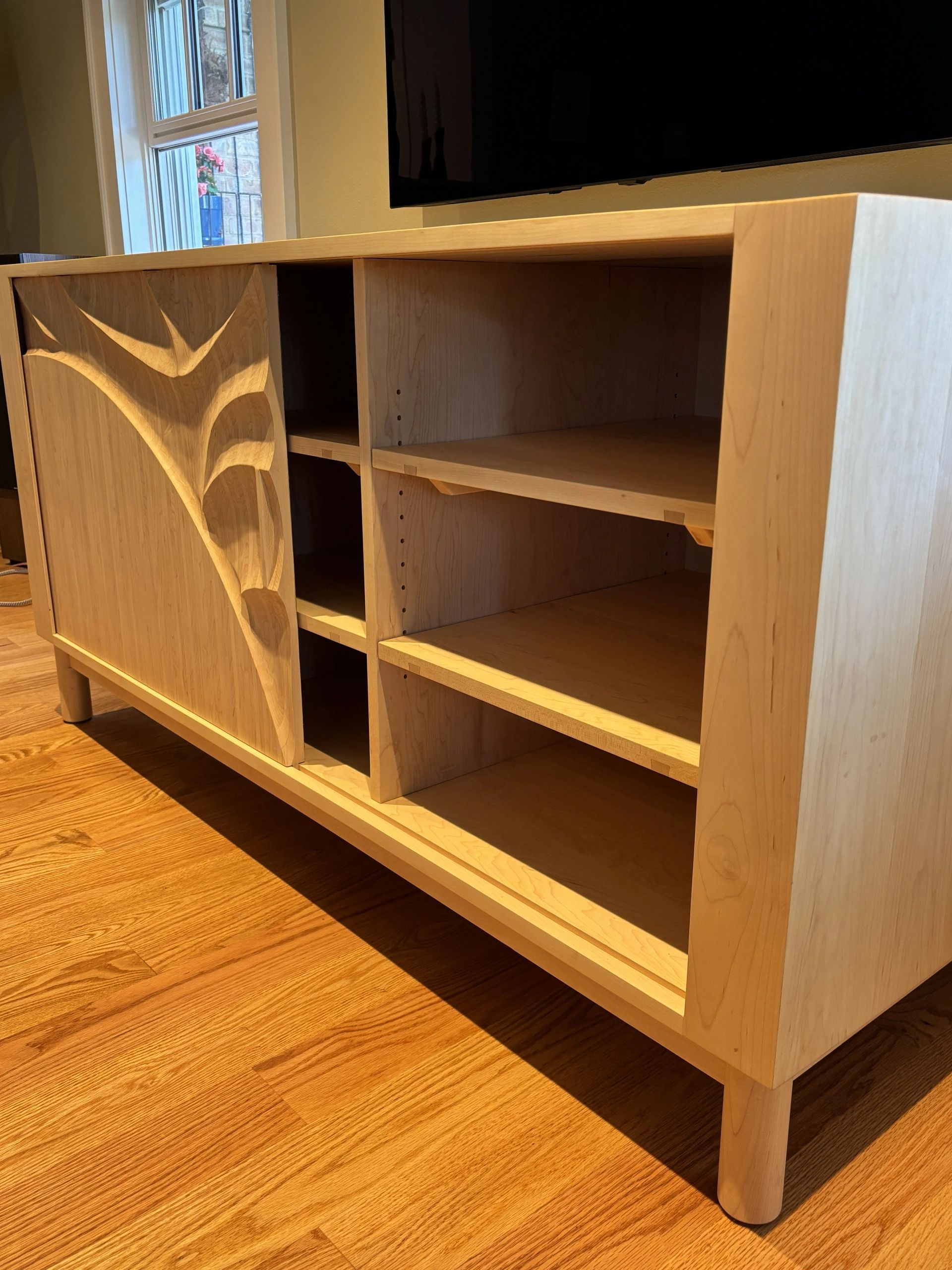 Wooden cabinet with carved door and shelves.