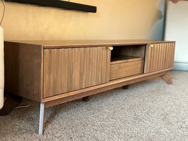 Wooden TV stand with storage cabinets and drawer.