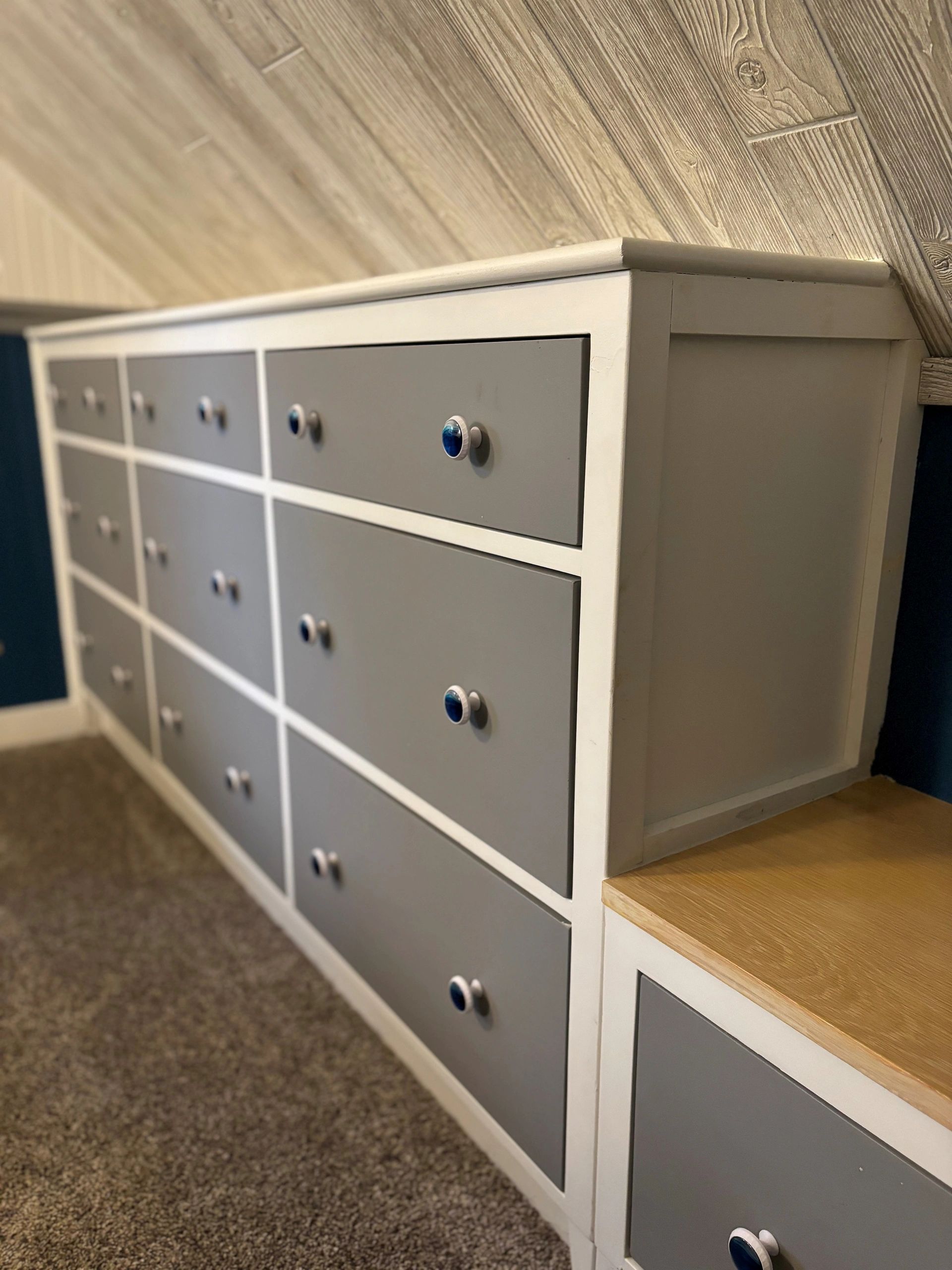 Modern dresser with gray drawers and blue knobs.