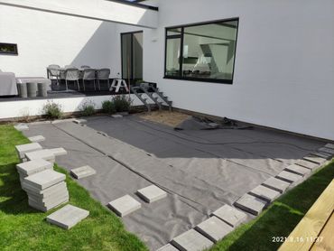 Fugmann Byg forbereder ny flisebelægning til terrasse ved moderne hvid villa i Aalborg.