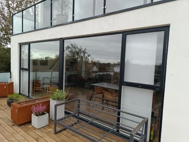 Moderne terrasse og facade med store vinduespartier – bygget af Fugmann Byg ApS i Aalborg.