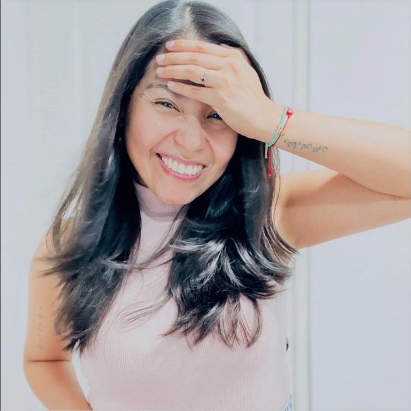 Mujer sonriente con mano en la frente.