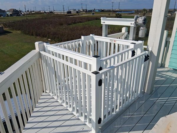 Cargo lift installed on beach house with custom gates and white powder coating to match house deck.