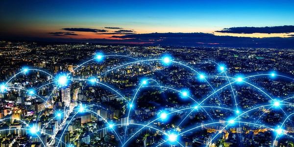 This photo depicts a city at night that is connected through illuminated blue light strings.
