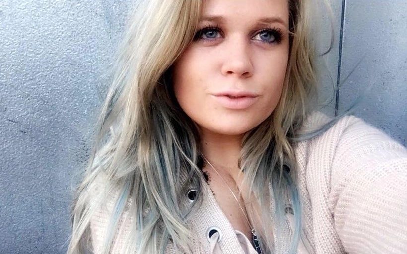 Young woman with blonde hair and blue eyes taking a selfie.