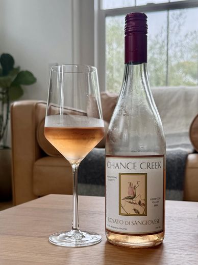 A glass and bottle of Chance Creek Rosato di Sangiovese wine on a table.