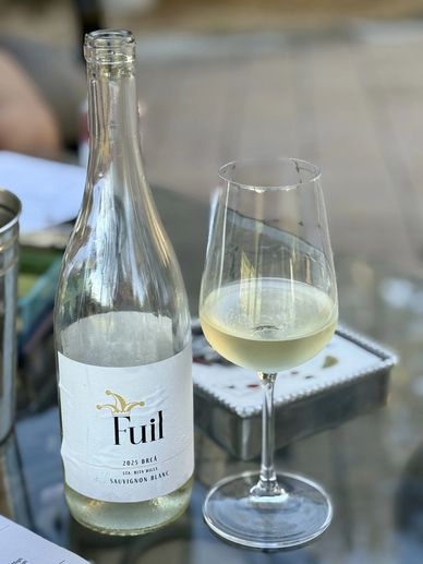 A bottle and glass of Sauvignon Blanc wine on a table.