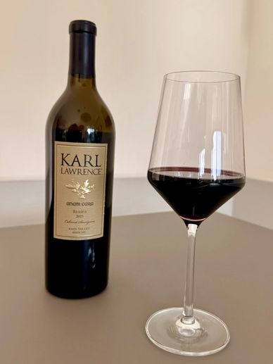 A bottle of Karl Lawrence wine with a glass of red wine on a table.