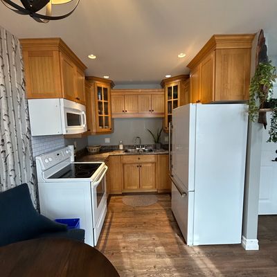 Compact kitchen with wooden cabinets and white appliances.