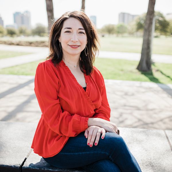 Woman in red blouse sitting outdoors on a sunny day.