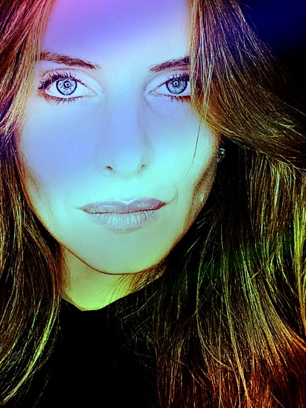 Close-up portrait of a woman with vibrant lighting and intense eyes.