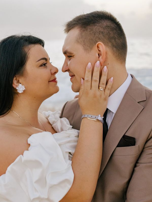 A couple lovingly gazing at each other, celebrating their wedding by the sea.