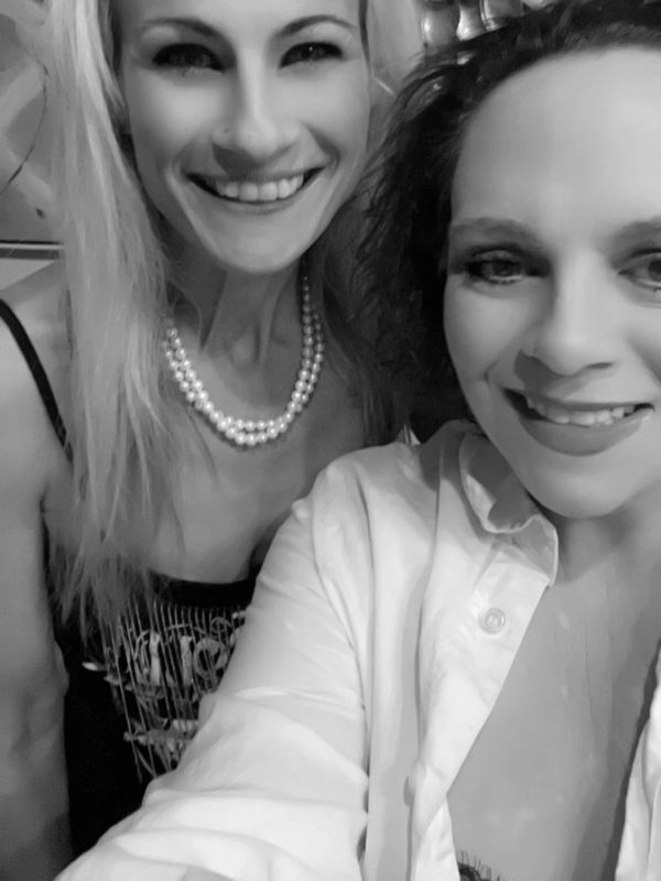 Two smiling women posing for a close-up selfie indoors.