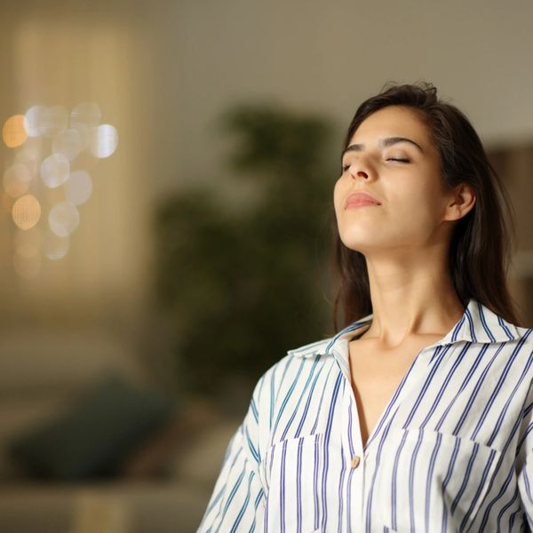 Woman with closed eyes enjoying a peaceful moment indoors.